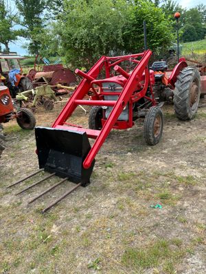 un tracteur rouge attelé à une charrue dans un champ
