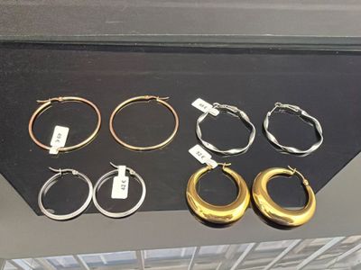 several pairs of gold and silver hoop earrings on display in a glass case
