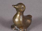 un petit canard en bronze posé sur une table