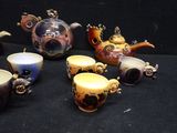 many different teapots and cups sitting on a black surface