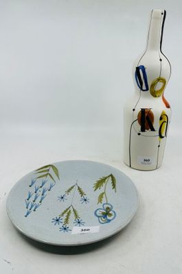 une assiette décorée d'un motif, à côté d'une bouteille de vin