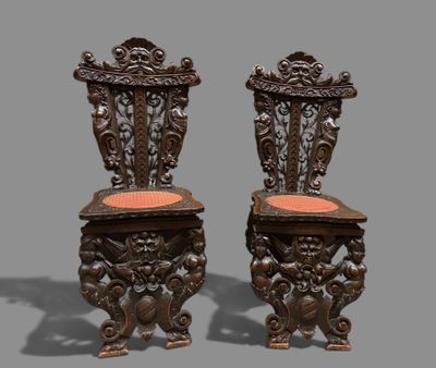 pair of antique carved wood chairs with orange upholstered cushions