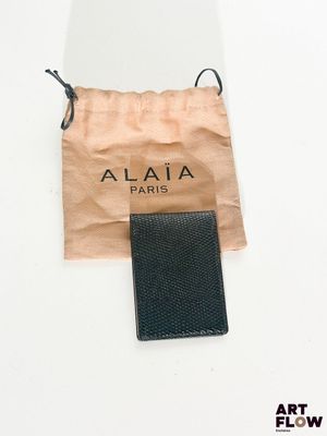 un portefeuille noir et un sac marron posés sur une surface blanche