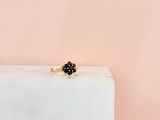 une photo d'une bague en diamant noir posée sur un bloc blanc