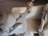 a statue of a woman playing a guitar next to a statue of an angel