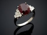 a close up of a ring with a red stone and diamonds