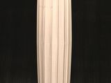 un grand vase blanc posé sur un socle en bois, sur fond noir