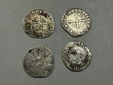 quatre pièces d'argent ornées d'une couronne, posées sur une table