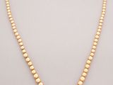 a gold beaded necklace on a white background