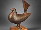 une sculpture en bronze représentant un oiseau, posée sur un socle en bois