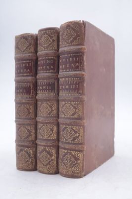 trois vieux livres sont empilés sur une surface blanche