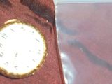 une montre de poche posée sur un tissu marron