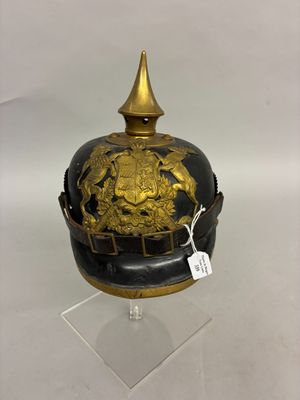 an antique helmet with gold decoration on a clear base