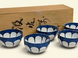 four blue and white bowls sitting in front of a wooden box
