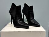 a pair of black leather ankle boots sitting on top of a white box