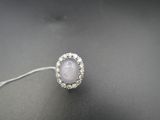 un gros plan d'une bague ornée d'une pierre blanche entourée de diamants