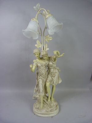 une statue représentant une femme et un homme tenant une lampe