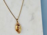 un gros plan d'un collier « Gold Locke » posé sur une surface en marbre