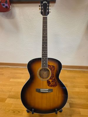 a close up of a guitar on a stand on a hard wood floor
