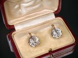 deux paires de boucles d'oreilles en diamant dans un écrin rouge posé sur un fond noir