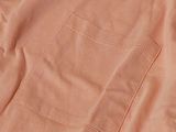 an orange t - shirt with a tag on it sitting on top of a table