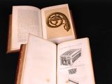 two open books sitting on a table with a snake on top of them