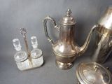 a silver tea pot and four glasses on a table