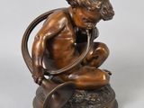 bronze figurine of a boy with a snake on a pedestal