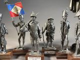 several metal figurines of soldiers holding flags and standing on wooden bases
