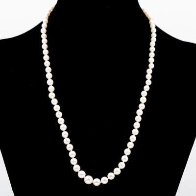 un collier de perles blanches autour du cou d'un mannequin, muni d'un fermoir en or