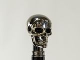silver skull on a black cane on a white background