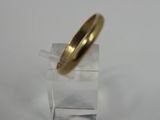 a close up of a gold wedding ring on a clear stand