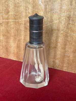 a small glass bottle with a toothbrush inside of it on a red surface