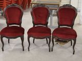 Six chaises rouges sont alignées en rang dans une pièce