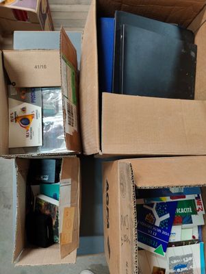 Plusieurs cartons remplis de livres sont empilés les uns sur les autres par terre.