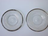 paire d'assiettes en verre transparent à bordure argentée, posées sur un plateau blanc