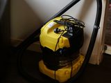 un aspirateur jaune et noir posé par terre à côté d'une chaise noire