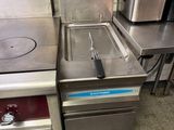 stainless steel kitchen equipment including a fryer, stove, and sink