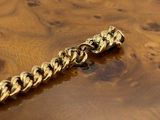 gold chain bracelet on a wooden table on a white background