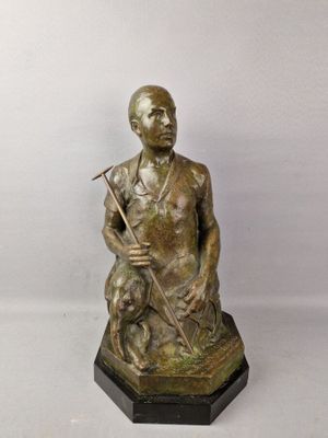 statue en bronze représentant un homme avec un chien, posée sur un socle