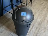 a black trash can sitting on the floor next to a brown chair