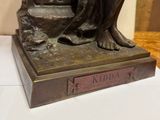 bronze statue of a woman sitting on a chair with a book