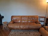 un canapé en cuir marron dans un salon où se trouve un tapis au sol