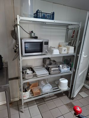 une cuisine équipée d'un micro-ondes et d'une étagère sur laquelle sont posés des plats