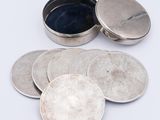 several silver coins sitting on top of each other on a white surface