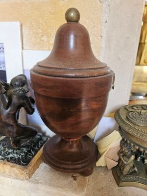 une urne en bois posée sur une table à côté d'une statue