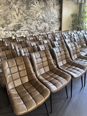 Plusieurs fauteuils en cuir marron sont alignés en rangée dans une salle d'attente