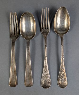 four silver spoons and two forks are lined up on a gray surface