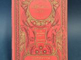 a red book with gold writing on it sitting on a blue surface