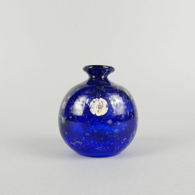 un vase bleu posé sur une table à fond blanc